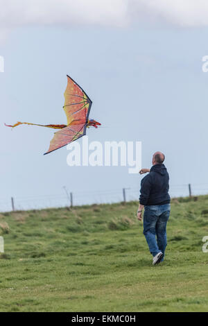 Wiltshire, UK. 12th April, 2015. UK Weather: Strong blustery winds high upon the landmark chalk White Horse above the town of Westbury. The strong winds did not stop many members of the public from visiting and making use of the weather to hike, walk pet dogs, fly kites and enjoy the stunning views across the Wiltshire vale.  The site is protected by English Heritage who maintain the ancient Iron Age hill fort seasonally by allowing grazing flocks of sheep to maintain favourable chalk grasses and scrub plants.   Credit:  Wayne Farrell/Alamy Live News Stock Photo