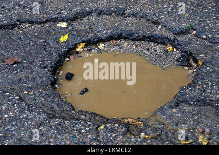 Pothole in a street filled with rain water. Stock Photo
