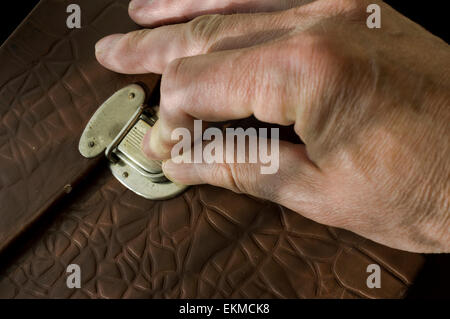 Male hand on a leather briefcase lock, concept of secrecy Stock Photo