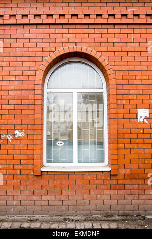 White painted arched window in a red brick wall Stock Photo