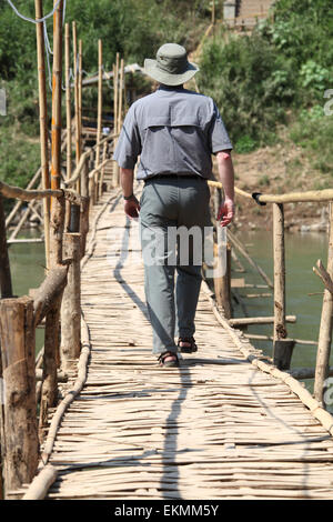 Traveller crossing a bamboo bridge over the Nam Khan river in Luang Prabang Stock Photo