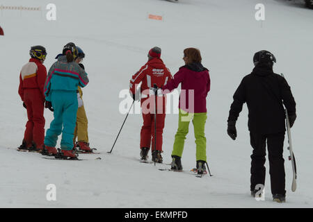 A pack of students being taught & learning how to ski down the alps by an instructor Stock Photo