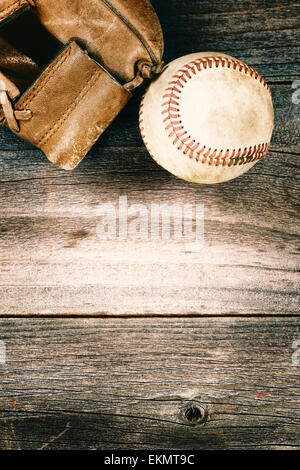 Vintage concept of an old baseball and weathered leather mitt on rustic wood. Format in vertical layout. Stock Photo