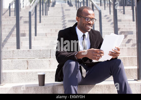 happy black businessman sitting with coffee and documents handling Stock Photo