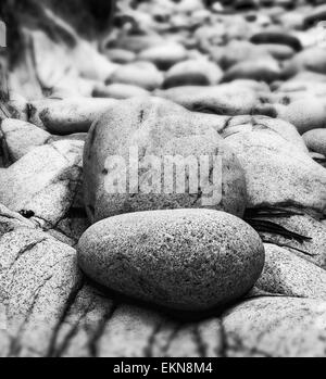 Tilt shift effect image with shallow depth of field textured rocks on beach black and white Stock Photo