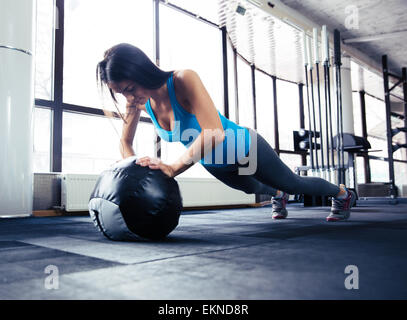 Young woman doing push up on fit ball at gym Stock Photo