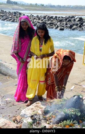 Three Indian Hindu women  wearing colourful worship a shrine at the Narbada River Shiva Festival Madhya Pradesh India Stock Photo
