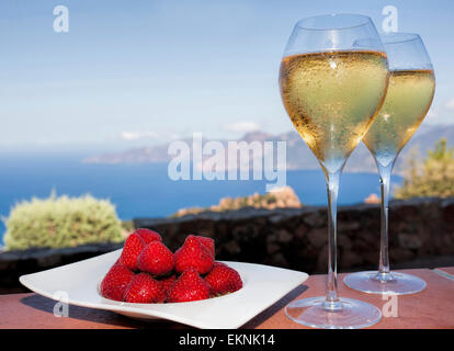 romantic drink in corsica with strawberries and white wine in two glasses and a view on the sea Stock Photo