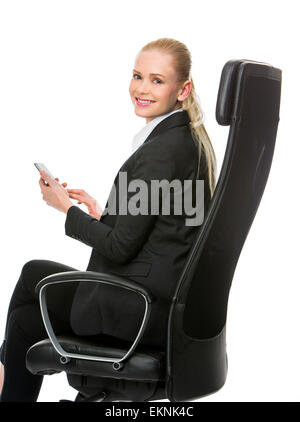 blonde smiling businesswoman seated on a chair working with tablet Stock Photo