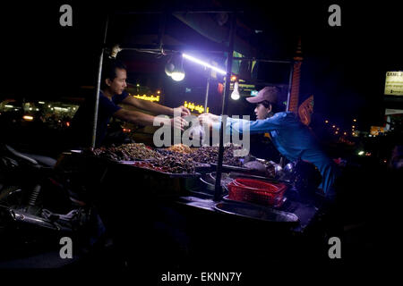 A man is selling deep fried insects as street food at night on a city street in Kampong Cham, Cambodia. Stock Photo