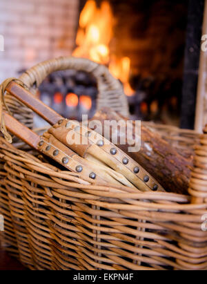 Bellows in a wicker basket in front of an open fire. Stock Photo