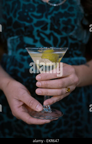 A woman holding a martini glass with a cocktail and a twist of lemon peel. Stock Photo