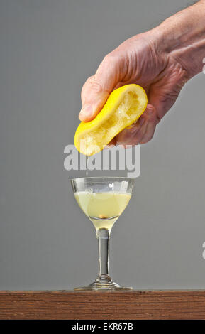 Man's hand squeezing half of lemon in a elegant glass Stock Photo