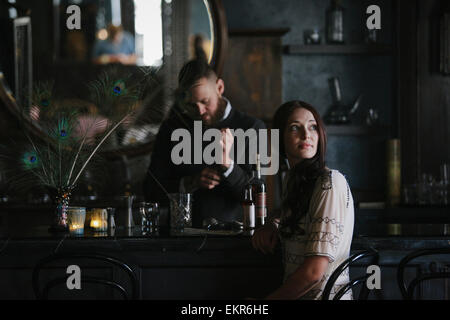 A woman and a bartender talking, and mixing drinks. Stock Photo