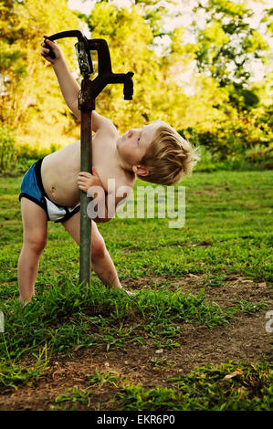 Boy looks for water in dry water pump Stock Photo