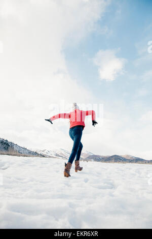 A girl with long legs running across the snow. Stock Photo