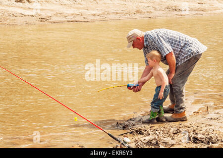 Grandfather teaching grandson to fish with toy rod and reel Stock Photo