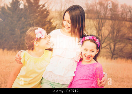 Three happy sisters together  in a meadow Stock Photo