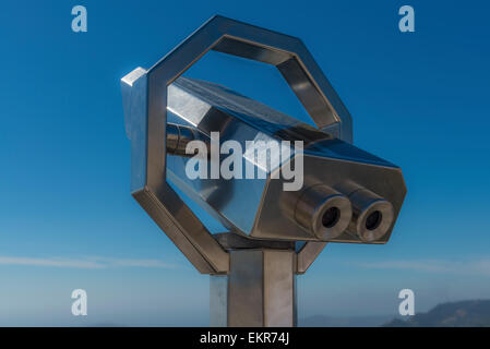 Shiny metal public viewing binoculars set against a blue sky Stock Photo