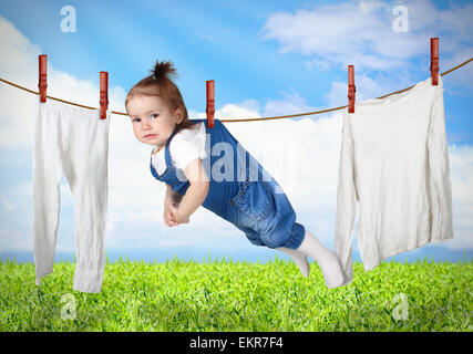 Funny child hanging on line with clothes, laundry creative concept Stock Photo