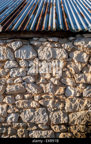 Rough stone wall with corrugated iron roofing - France. Stock Photo