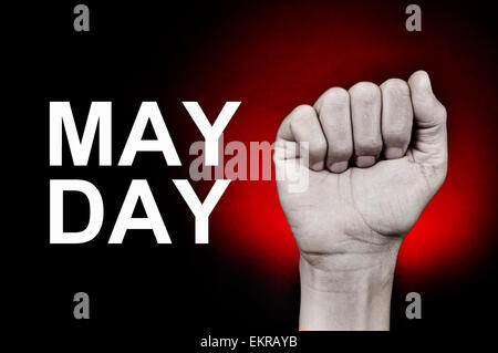 closeup of the raised fist of a young caucasian man and the text may day on a red background Stock Photo