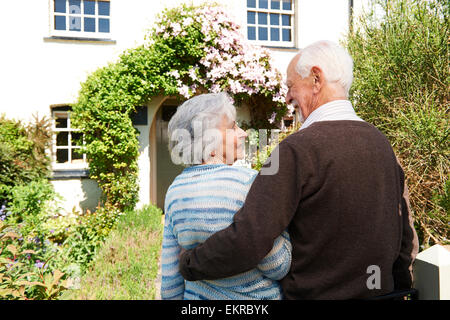 Rear View Of Senior Couple Outside Pretty Cottage Stock Photo