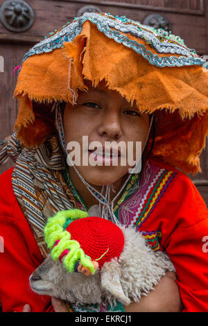 Peru, Cusco.  Young Quechua Girl in Traditional Dress, Holding Pet Lamb. Stock Photo