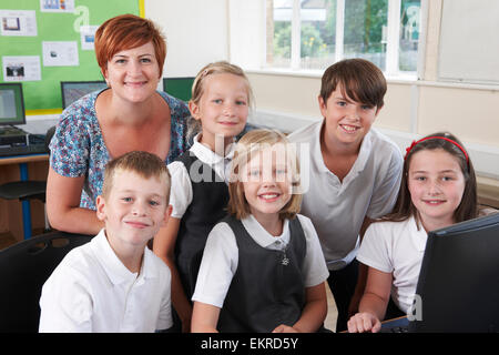 Group Of Elementary Pupils In Computer Class With Teacher Stock Photo