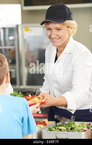 Pupil In School Cafeteria Being Served Lunch By Dinner Lady Stock Photo