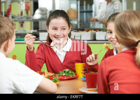 Group Of Pupils Sitting At Table In School Cafeteria Eating Lunch Stock Photo