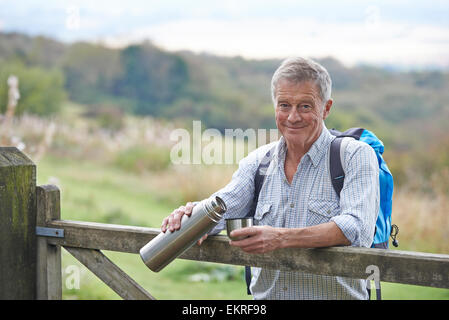 Senior Man Having Drink From Flask Whilst On Walk Stock Photo