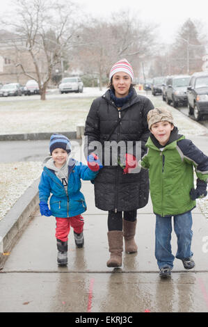 Hispanic mother walks down the street with her two boys ages seven and four. Stock Photo