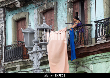 Woman in Havana,Cuba,hanging up her washing on the balcony opposite the Capitolio building Stock Photo