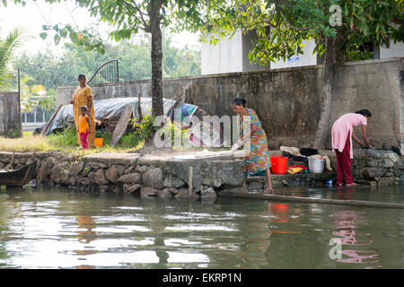 Women washing their laundry and dishes in the Backwaters of Kumarakom, Kerala India Stock Photo