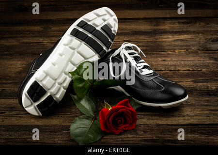 black man's shoes and rose on wooden background Stock Photo