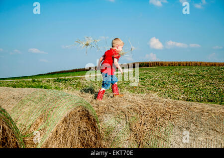 Boy walking on haybales Stock Photo