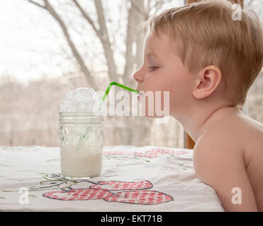 boy blows milk bubbles in his glass Stock Photo