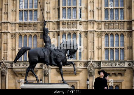 Orthodox Jewish men with the statue of King Richard 1st while visiting the exterior of Britain's parliament in Westminster, London. Richard Coeur de Lion is a Grade II listed equestrian statue of the 12th-century English monarch Richard I, also known as Richard the Lionheart, who reigned from 1189–99. It stands on a granite pedestal in Old Palace Yard outside the Palace of Westminster, facing south towards the entrance to the House of Lords. It was created by Baron Carlo Marochetti, Stock Photo