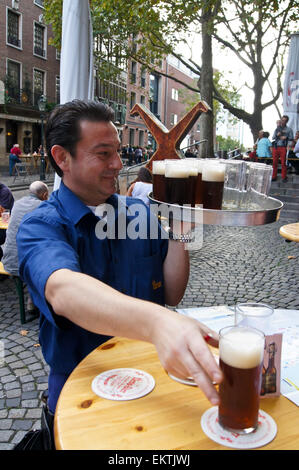 Köbes (barman) serving Altbier at Uerige brauhaus, Düsseldorf, Nordrhein-Westfalen, Germany pub table drinks glasses Stock Photo