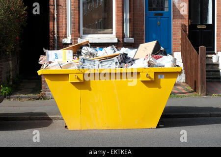 yellow rubbish skip on road outside terraced house Stock Photo