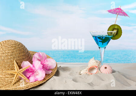 Blue cocktail on the beach with a sunhat and sea shells Stock Photo