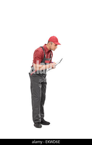 Full length portrait of a mechanic in a gray jumpsuit writing down notes on a clipboard isolated on white background Stock Photo