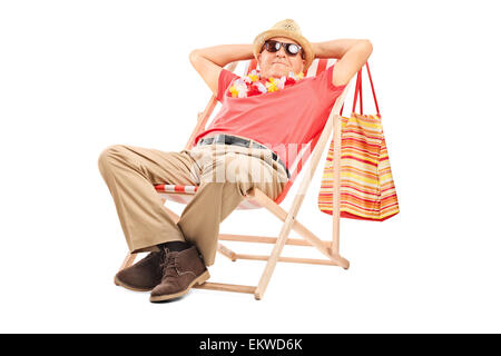 Relaxed senior gentleman with sunglasses sitting in a comfortable sun lounger chair isolated on white background Stock Photo