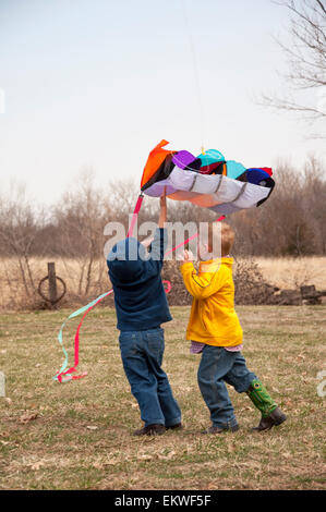 Two boys work to get a kite in the air Stock Photo