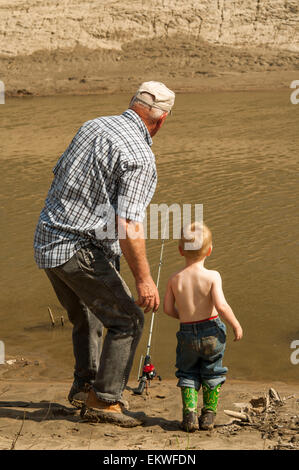grandfather and grandson watching fishing pole for bite Stock Photo