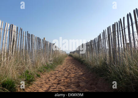 Sandy footpath with a blue sky and wooden fence UK Stock Photo