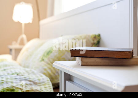 bedroom with books on nightstand Stock Photo