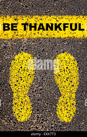 Be Thankful message. Conceptual image with yellow paint footsteps on the road in front of horizontal line over asphalt Stock Photo