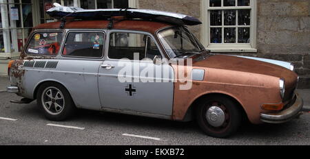 Old beat up car with Bansky Rat in side window and other stickers and surf board on roof Stock Photo